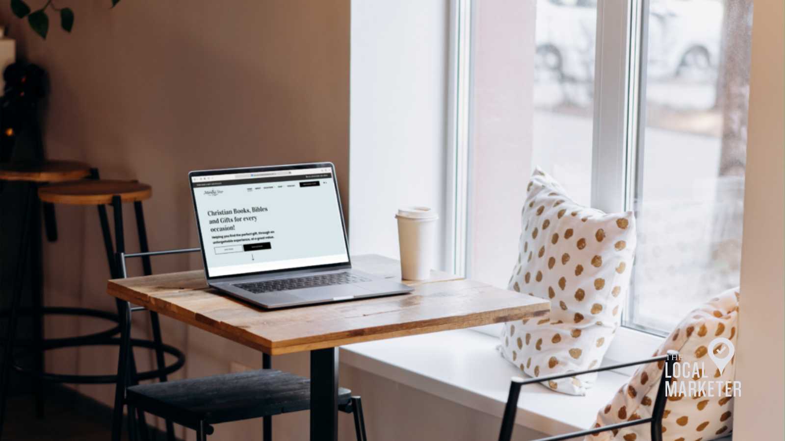 Laptop displaying Morning Star Christian bookstore website on a wooden table in a cozy café setting, featuring decorative pillows and a coffee cup, emphasizing e-commerce and web design for Christian businesses.